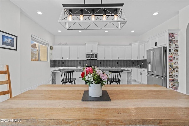 kitchen featuring decorative light fixtures, tasteful backsplash, a center island, stainless steel appliances, and white cabinets