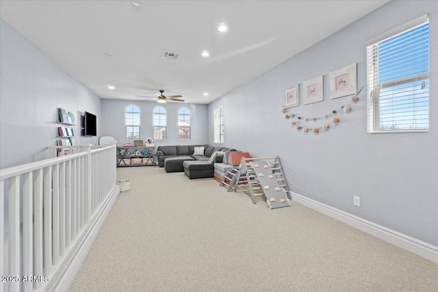 living room featuring ceiling fan, carpet, and a healthy amount of sunlight