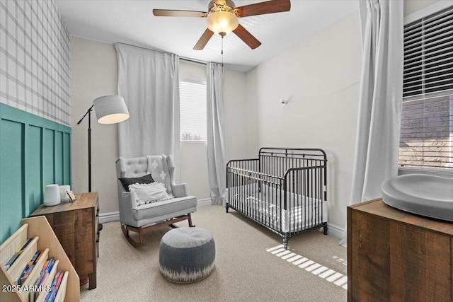 bedroom with ceiling fan, light colored carpet, and a crib