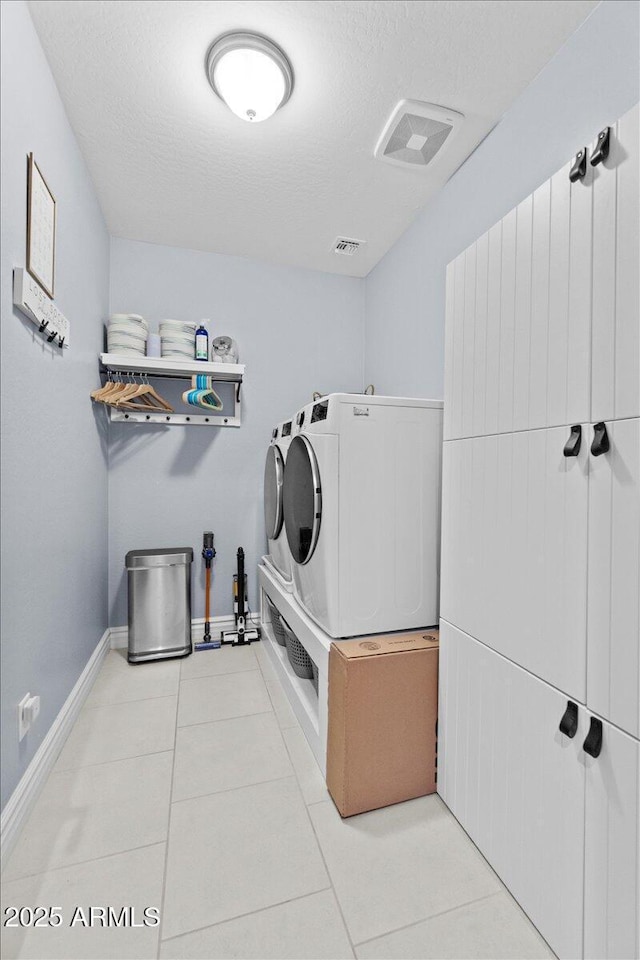 washroom with light tile patterned floors, washing machine and clothes dryer, and a textured ceiling