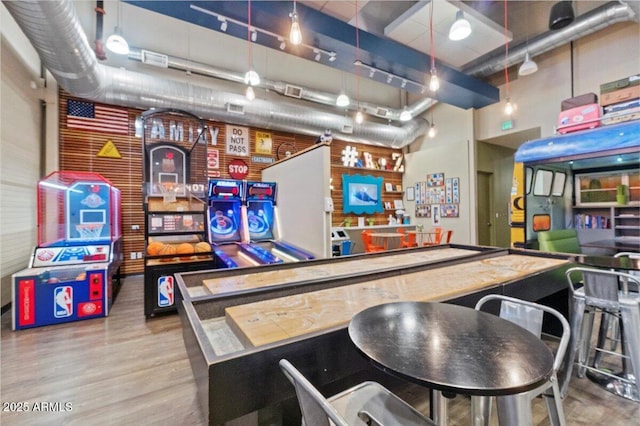 rec room featuring wood-type flooring and a towering ceiling