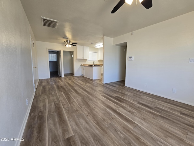 unfurnished living room featuring hardwood / wood-style flooring, ceiling fan, and sink