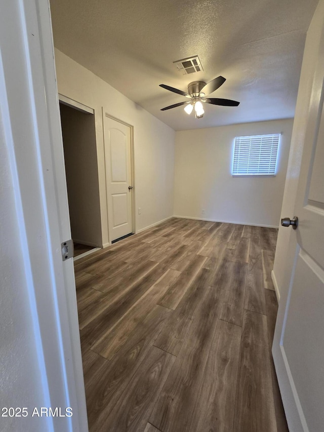 unfurnished bedroom with a textured ceiling, dark hardwood / wood-style floors, and ceiling fan