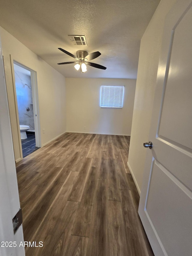 unfurnished room with ceiling fan, dark hardwood / wood-style flooring, and a textured ceiling