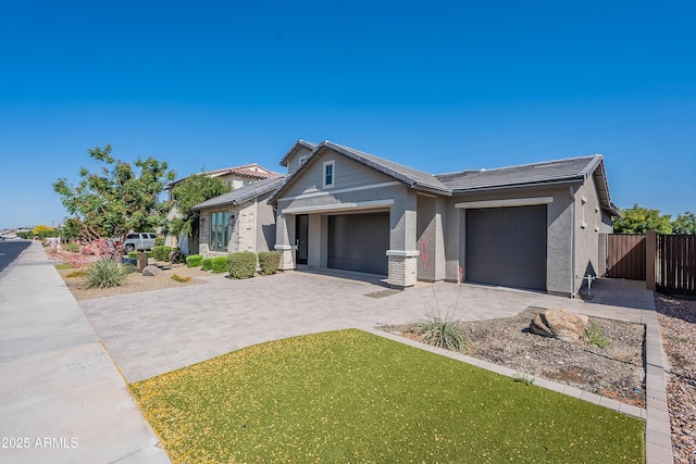 ranch-style home with a garage, decorative driveway, stucco siding, a gate, and a tile roof