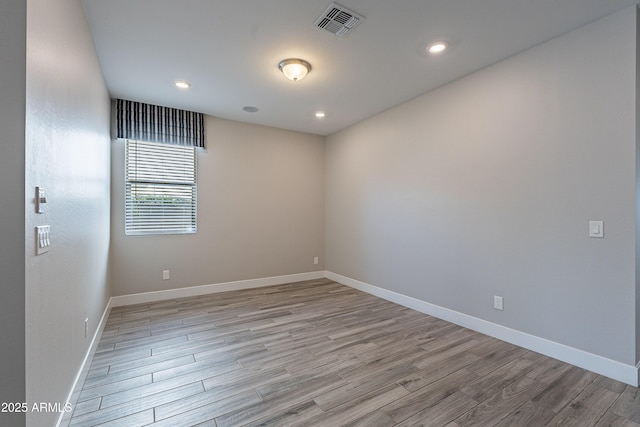 empty room featuring light wood-style flooring, baseboards, and recessed lighting