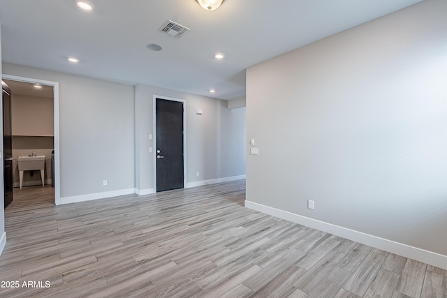 empty room with light wood-style floors, baseboards, and recessed lighting