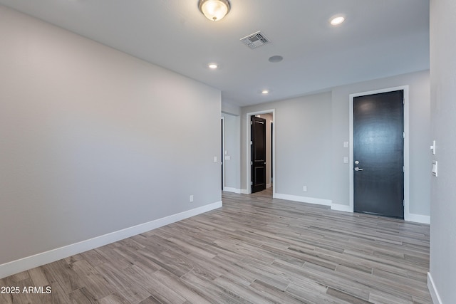 empty room featuring light wood-type flooring, baseboards, and recessed lighting