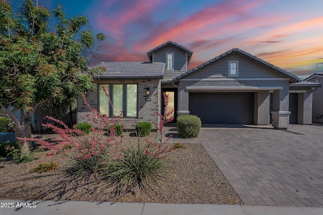 view of front facade featuring a garage, driveway, brick siding, and a tiled roof