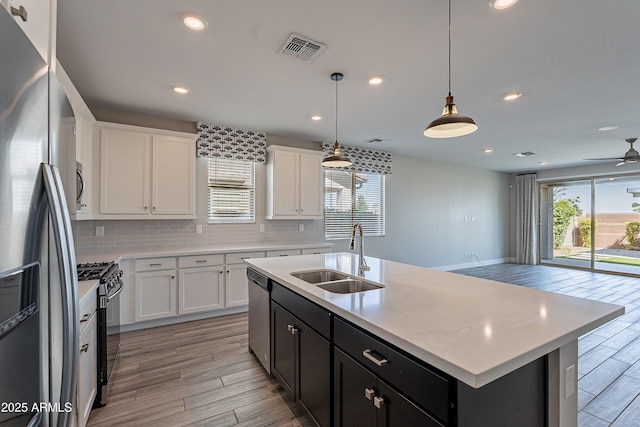kitchen with stainless steel appliances, a sink, light wood finished floors, backsplash, and recessed lighting