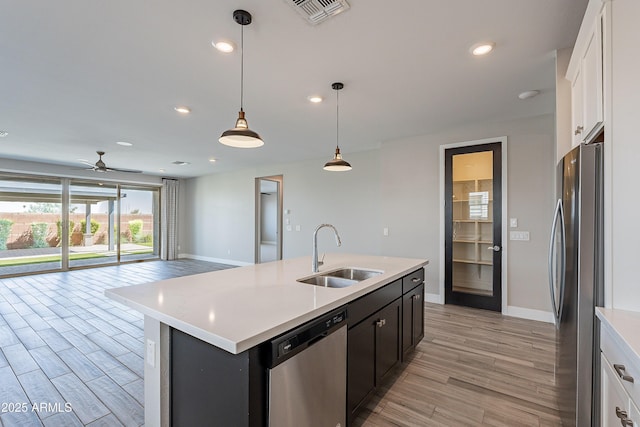 kitchen with a sink, stainless steel appliances, baseboards, light wood-style floors, and white cabinets