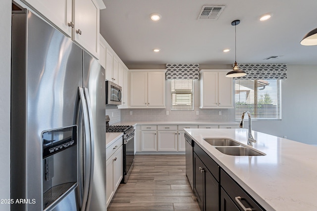 kitchen with stainless steel appliances, a sink, white cabinets, pendant lighting, and recessed lighting