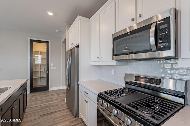kitchen featuring stainless steel appliances, decorative backsplash, white cabinets, light countertops, and recessed lighting