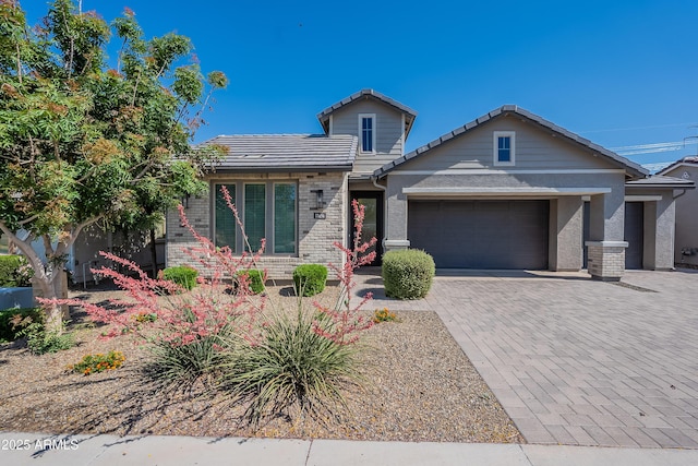 view of front of property with an attached garage, a tile roof, decorative driveway, and brick siding