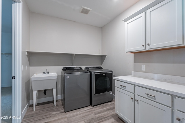 washroom featuring washer and dryer, cabinet space, light wood-style flooring, and baseboards