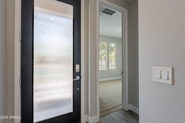 entryway with wood finished floors, baseboards, and a textured wall