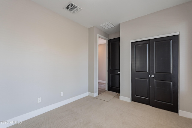 unfurnished bedroom with light colored carpet, baseboards, and a closet