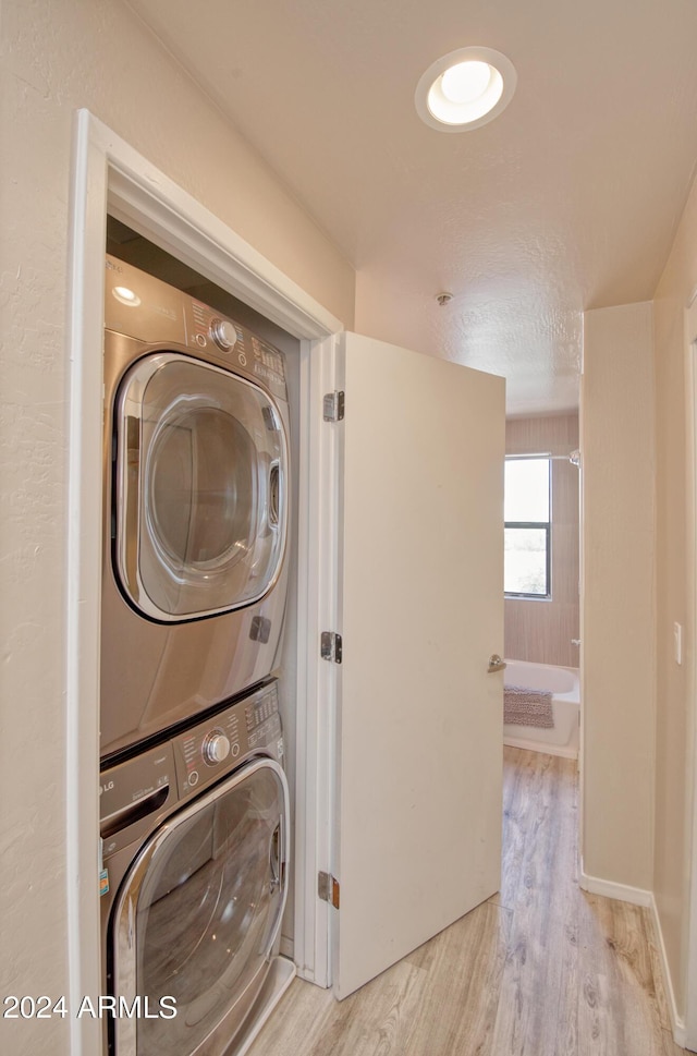 washroom with stacked washer and dryer and light hardwood / wood-style floors