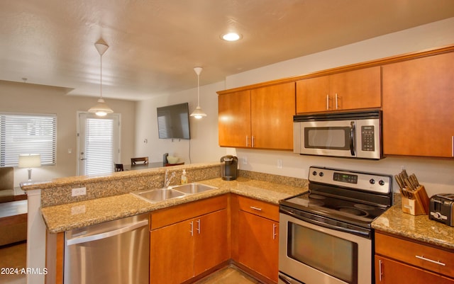 kitchen with pendant lighting, sink, kitchen peninsula, and appliances with stainless steel finishes