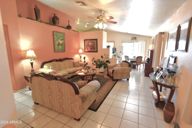 living room with ceiling fan, light tile patterned floors, a textured ceiling, and vaulted ceiling