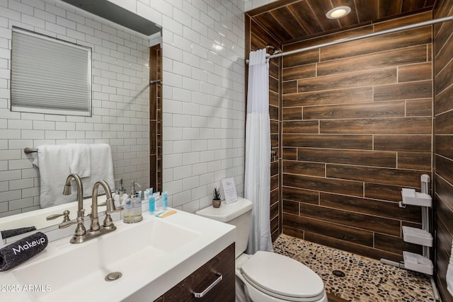 full bath with a stall shower, tile walls, vanity, and toilet