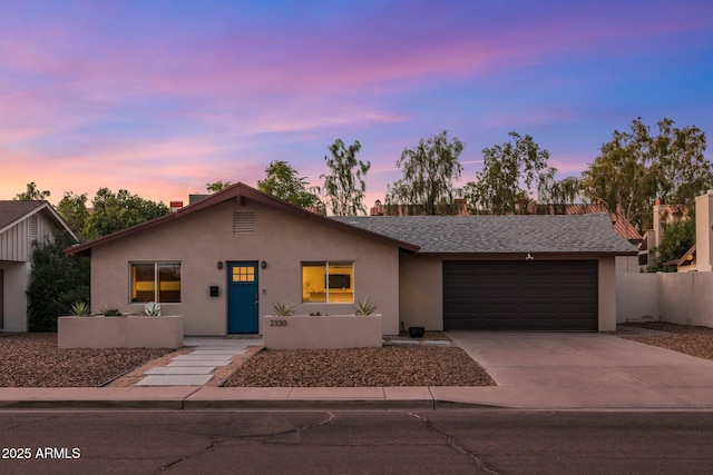 view of front of house with stucco siding, a shingled roof, concrete driveway, fence, and a garage