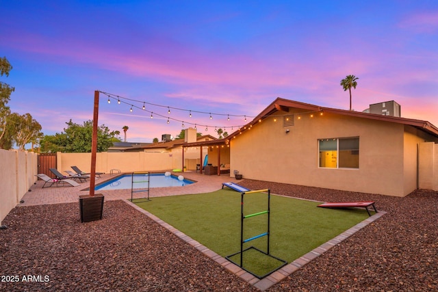 playground at dusk with a patio area, a fenced backyard, a fenced in pool, and a yard