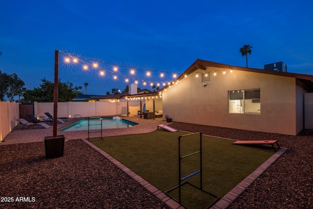 pool at twilight with a patio, a yard, a fenced backyard, and a fenced in pool