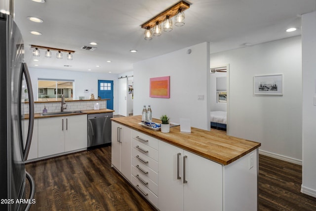 kitchen with visible vents, appliances with stainless steel finishes, white cabinetry, wooden counters, and a sink