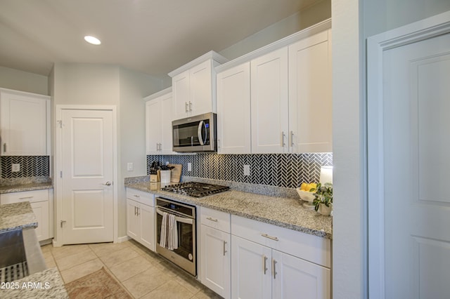 kitchen featuring tasteful backsplash, light tile patterned floors, white cabinetry, and stainless steel appliances