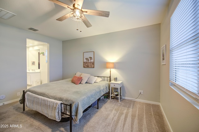 bedroom with light carpet, baseboards, visible vents, and ensuite bath
