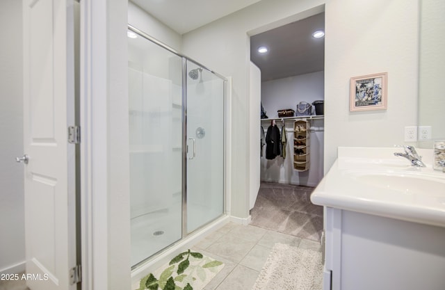 bathroom featuring vanity, recessed lighting, a walk in closet, a stall shower, and tile patterned floors