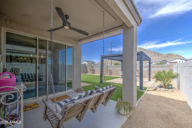 view of patio with a mountain view, a fenced backyard, and a ceiling fan