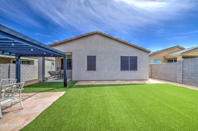 rear view of house featuring a patio, stucco siding, fence, and a lawn