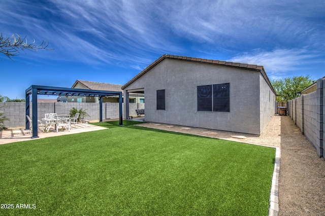 rear view of house featuring a patio, a yard, a fenced backyard, and stucco siding
