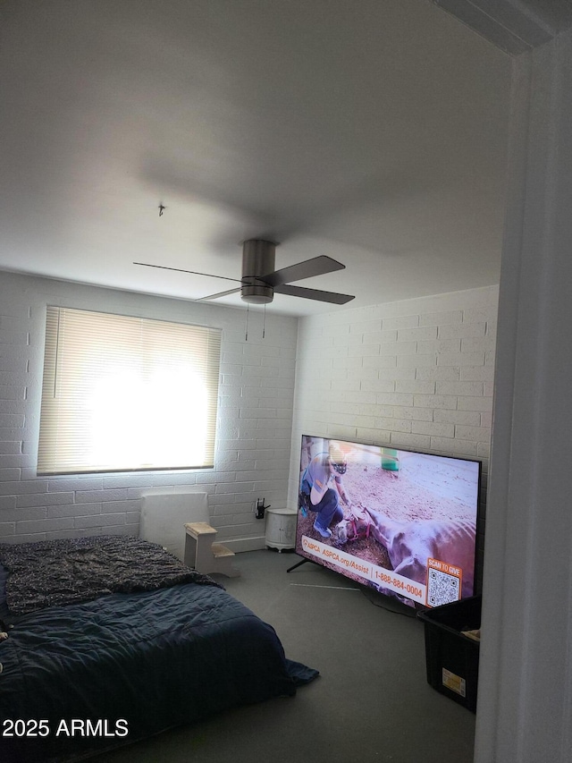 bedroom with ceiling fan and brick wall