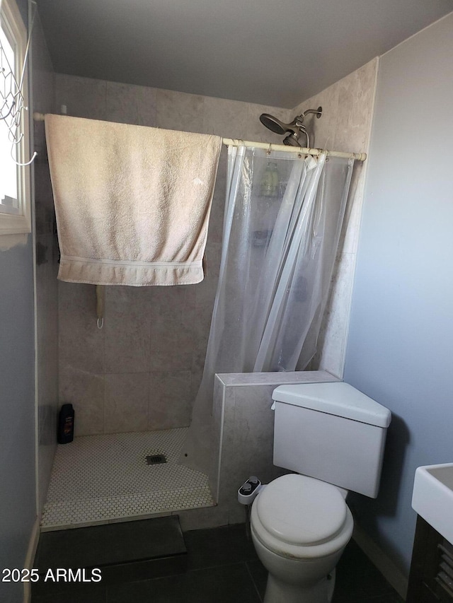 bathroom with tile patterned flooring, a shower stall, and toilet