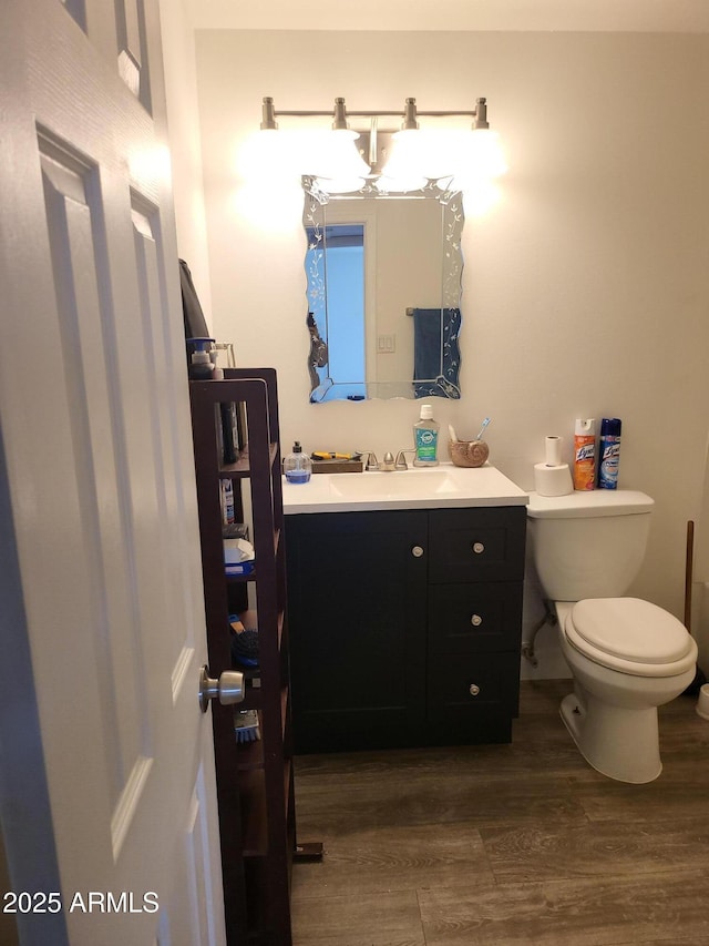 bathroom featuring toilet, wood finished floors, and vanity