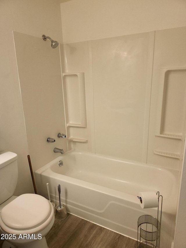 bathroom featuring toilet, wood finished floors, and bathing tub / shower combination