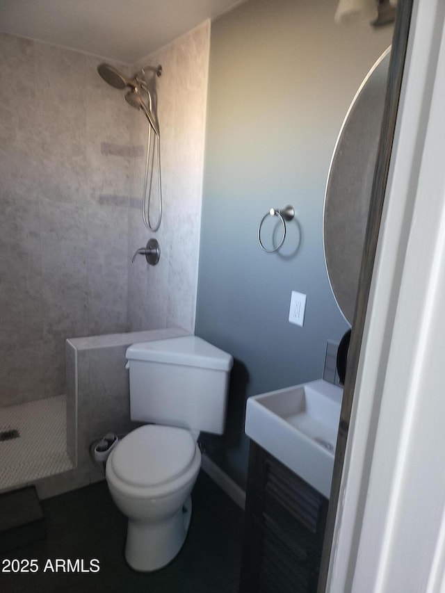 full bathroom with toilet, a tile shower, and vanity