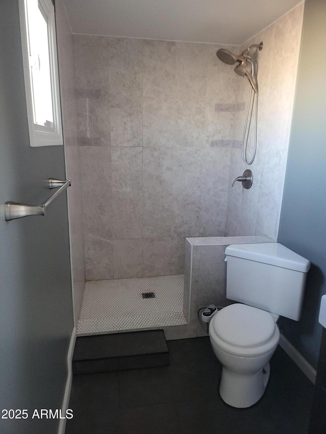 bathroom featuring tile patterned floors, a shower stall, toilet, and baseboards