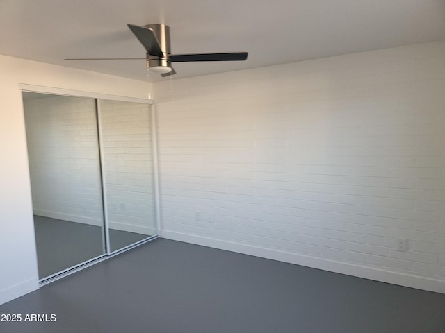 unfurnished bedroom featuring finished concrete flooring, baseboards, a ceiling fan, and a closet