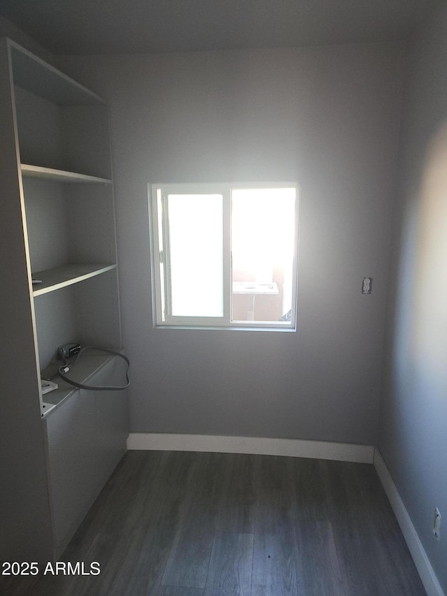 spare room with baseboards and dark wood-style flooring