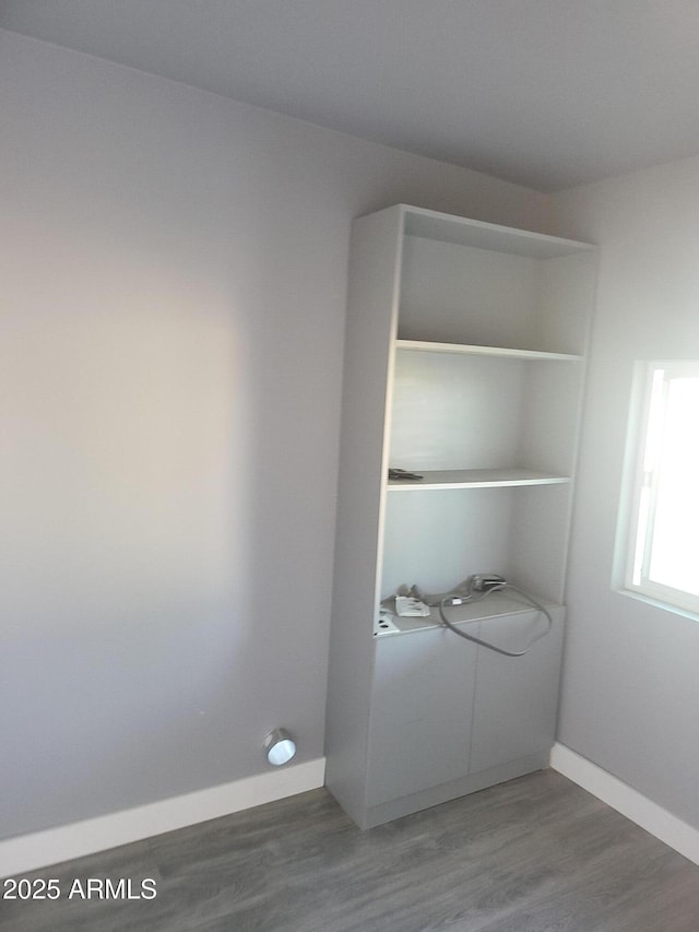 clothes washing area with laundry area, baseboards, washing machine and clothes dryer, and wood finished floors