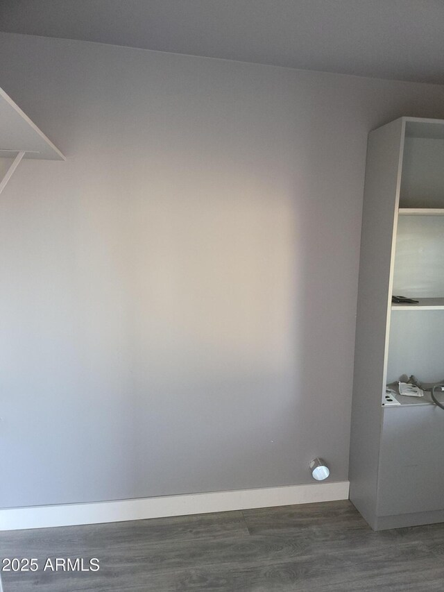 clothes washing area with dark wood-style floors and baseboards