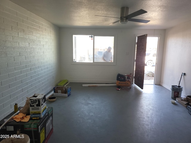 interior space with concrete floors, a ceiling fan, and a textured ceiling