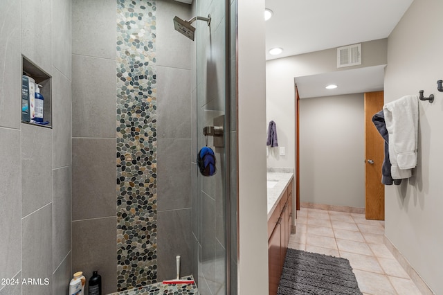 bathroom with tiled shower, tile patterned flooring, and vanity