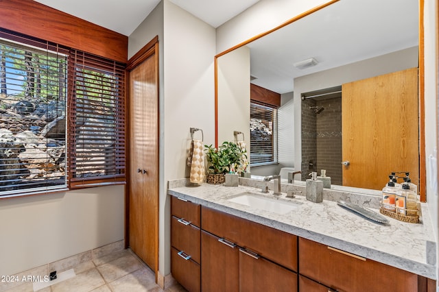 bathroom featuring tiled shower, tile patterned flooring, vanity, and a healthy amount of sunlight