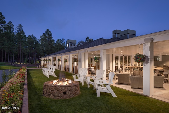 exterior space featuring a lawn, an outdoor living space with a fire pit, and a patio area