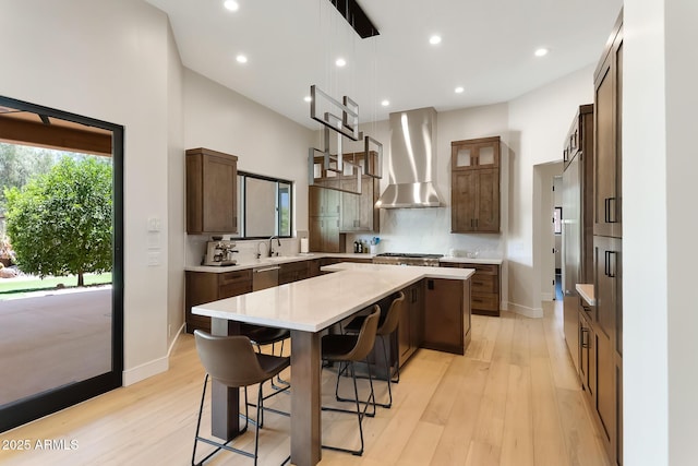 39419 N 7th Ave, Phoenix, AZ 85086 - kitchen featuring wall chimney range hood, a kitchen island, appliances with stainless steel finishes, light countertops, and light wood-style floors